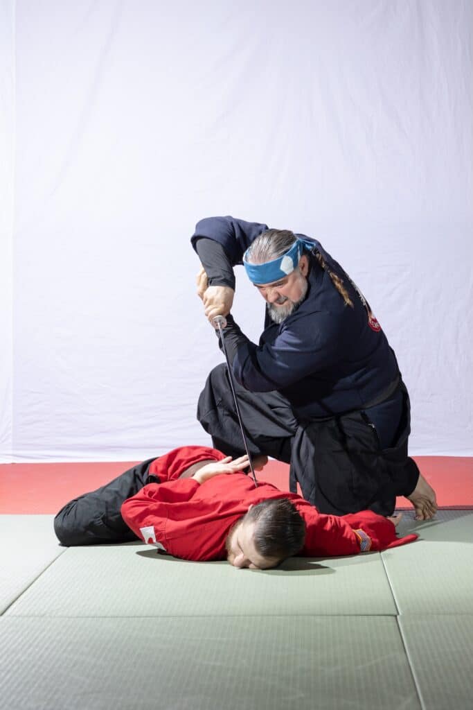 instructor at homeland heroes holding a sword to student during demonstration for class